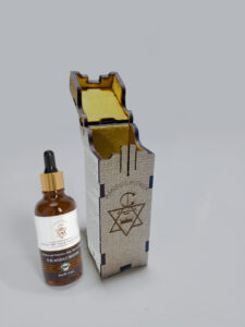 Small amber dropper bottle of Moroccan Argan Oil from Amigos Power with gold cap, placed on a light background.